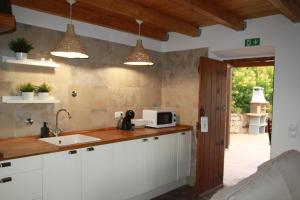 a kitchen with white cabinets and a sink and lights at Corvatos Casas do Monte in Almodôvar