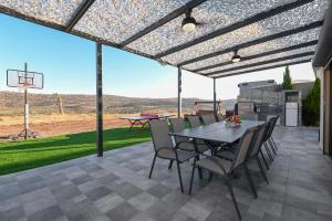 een patio met een tafel en stoelen en een basketbalring bij נופש הלל - בית נופש עם ממ"ד, בריכה מחוממת וג'קוזי - 15 דק מהכנרת in Kallanit