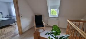 una habitación con una silla negra y una escalera en Ferienwohnung "Gartenblick" Wolzhausen en Breidenbach