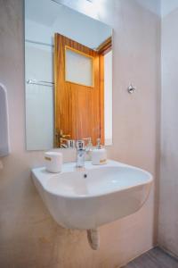 Hotel Korfos - Ξενοδοχείο Κόρφος Renovated في كورفوس: بالوعة بيضاء في الحمام مع مرآة