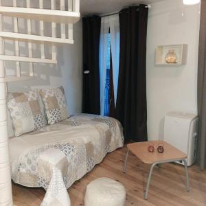 a small bedroom with a bed and a table at Le Triplex Pézenas in Pézenas