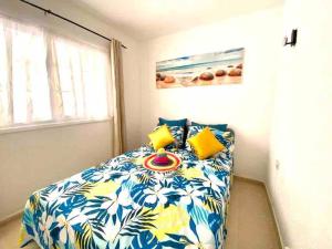 een slaapkamer met een bed met een blauwe en gele deken bij Confortable y céntrico in Los Cristianos