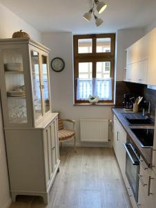 a kitchen with white cabinets and a clock on the wall at AltstadtQuartier Burg in Burg bei Magdeburg