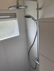 een douche met een douchekop in de badkamer bij Lauwersmeer 120 in Lauwersoog