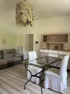 sala de estar con mesa de cristal y sillas blancas en Novecento Charming Room, en Avigliana