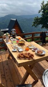 une table en bois avec de la nourriture sur une terrasse dans l'établissement Elit Bungalov, à Ardeşen