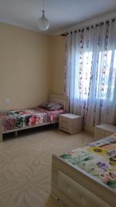 a room with two beds and a window with curtains at Guesthouse Isolde in Vlorë