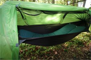 una tenda verde con amaca all'interno. di Baumzeltdorf OSTSEEBREEZE direkt am Strand a Dranske