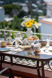 une table avec des tasses et un vase avec des fleurs. dans l'établissement Casa Rubina, à Capri