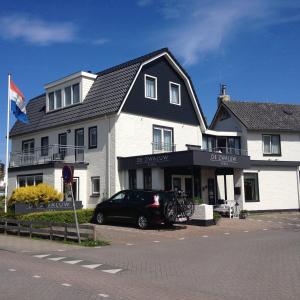 a black car parked in front of a white building at Boutique Hotel de Zwaluw in De Koog
