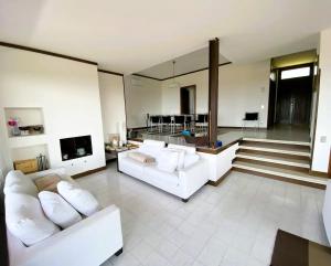a living room with two white couches and a staircase at VILLA SETTANTA Lago di Garda - Heated Pool on request in Bardolino