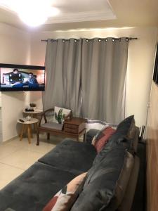 uma sala de estar com um sofá e uma televisão em A Passos da Areia Apartamento 2 Quartos no Coração da Badalada Praia do Morro - WiFi Fibra e Netflix para sua Estadia em Guarapari
