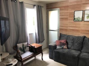 uma sala de estar com um sofá e uma cadeira em A Passos da Areia Apartamento 2 Quartos no Coração da Badalada Praia do Morro - WiFi Fibra e Netflix para sua Estadia em Guarapari