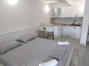 a bedroom with a bed and a kitchen with white cabinets at Apartments Lumbarda in Lumbarda