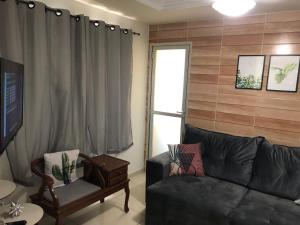 uma sala de estar com um sofá preto e uma janela em A Passos da Areia Apartamento 2 Quartos no Coração da Badalada Praia do Morro - WiFi Fibra e Netflix para sua Estadia em Guarapari