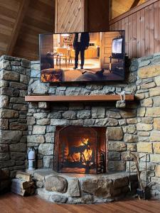 a stone fireplace with a tv on top of it at Abundant Acres Retreat in Beech Mountain