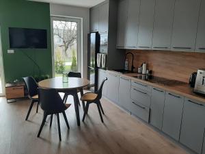 uma cozinha com mesa e cadeiras e uma cozinha com armários brancos em Apartament na Młyńskiej em Busko-Zdrój