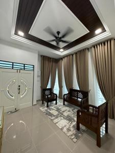 a living room with two chairs and a ceiling fan at Syakila Homestay in Marang