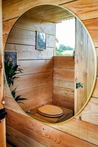 um quarto de madeira com um WC num espelho redondo em La Belle Ronde 