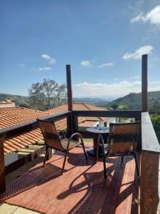 a patio with two chairs and a table on a deck at Chácara dos Ypes in Bueno Brandão