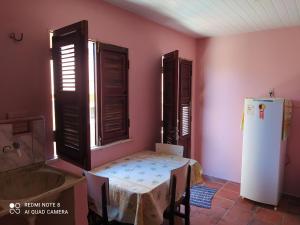 a kitchen with a table and a refrigerator in a room at Suítes D'Belinha in Canoa Quebrada
