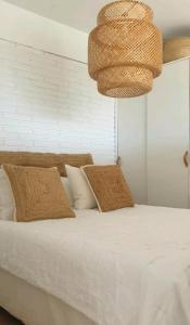 a bedroom with a bed with white sheets and a chandelier at PRECIOSO APARTAMENTO VISTAS AL MAR in Platja  d'Aro