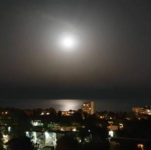 Una luna en el cielo sobre una ciudad por la noche en PRECIOSO APARTAMENTO VISTAS AL MAR, en Platja d'Aro