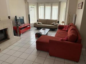 een woonkamer met een rode bank en een tv bij Chambres d'hôtes dans le Val d'Oise in Le Plessis-Bouchard