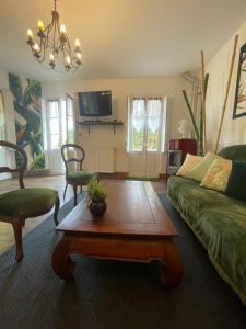 uma sala de estar com um sofá verde e uma mesa de centro em Domaine La Belle Histoire - Gîte côté Parc em Besset