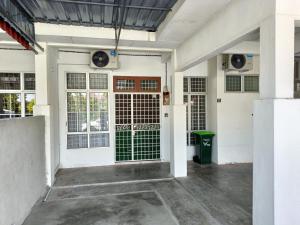 un garage blanc avec des portes et une poubelle verte dans l'établissement Adempuri Homestay 3, à Jitra