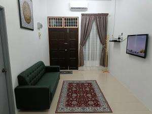 sala de estar con sofá verde y puerta en Adempuri Homestay 3 en Jitra