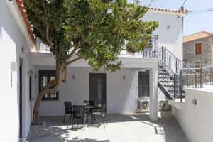 a courtyard with a table and chairs under a tree at Flonikos Apartmnets in Tsimándria