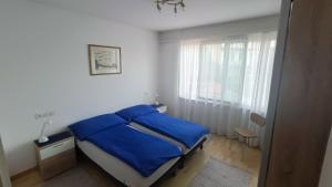 - une chambre avec un lit doté de draps bleus et une fenêtre dans l'établissement Casa Franceschini, à Locarno