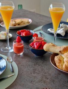 uma mesa com pratos de comida e dois copos de sumo de laranja em Villa la Dunette & spa em Vaux-sur-Mer