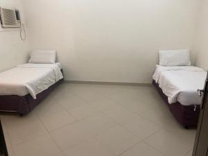 two beds in a room with white walls at هدى الحجاز للشقق المفروشة in Makkah