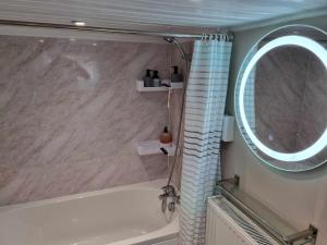 a bathroom with a tub and a round mirror at Ann's Garden flat in Deganwy