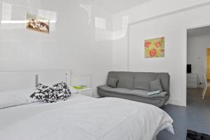 een witte slaapkamer met een bed en een bank bij Fantastic 2BD Barking stay with links to the City! in Londen