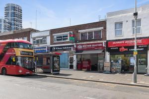 a red double decker bus parked at a bus stop at Fantastic 2BD Barking stay with links to the City! in London