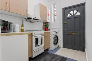 een keuken met een zwarte deur en een wasmachine bij Fantastic 2BD Barking stay with links to the City! in Londen