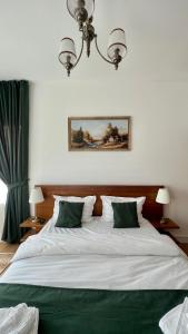 1 dormitorio con 1 cama blanca grande con almohadas verdes en Agropensiunea La Gradina en Baia-Sprie