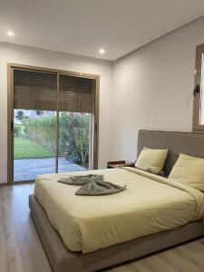 een slaapkamer met een groot bed en een groot raam bij appartement piscine in Marrakesh