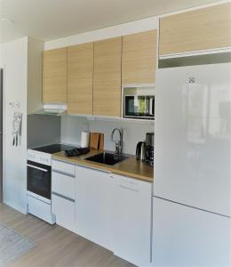 a kitchen with white appliances and wooden cabinets at Condo in the heart of Katariina, near Kotka City Center! in Kotka