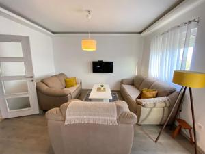 a living room with two couches and a tv at Home Mia Airport in Podgorica