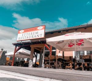 a restaurant with tables and umbrellas in front of it at Colosseum Étterem és Apartman Salgótarján in Salgótarján