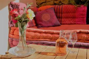 una mesa con un jarrón de flores y dos copas de vino en La Bucolique, Chambres et Jardin d'Hôtes en Sabran