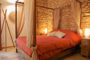 1 dormitorio con cama con dosel en una pared de piedra en La Bucolique, Chambres et Jardin d'Hôtes en Sabran