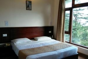 a bedroom with a bed and a large window at Mountain resort view in Kausani