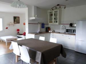 a kitchen with white cabinets and a table with white chairs at L'Esquerade in Castillon-de-Larboust