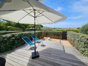 two chairs and an umbrella on a wooden deck at Zen et Mer in Le Grau-du-Roi