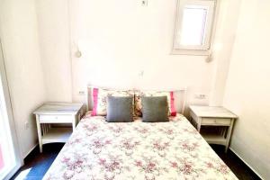a bedroom with a bed with two tables and a window at Cycladic House with Aegean View in Kalo Livadi
